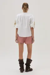 Camisa blanca de mezcla lino-algodón, con corte recto y mangas clásicas. Presenta un bordado floral en el hombro con distintas técnicas y canutillos.