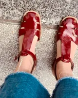 Sandalias rojas de cuero con tiras anchas y hebilla al tobillo.