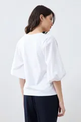 Remera blanca con escote en V y mangas balloon 3/4.