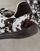 Zapatillas deportivas de cuero vacuno con estampado animal print de vaca en blanco y marrón.