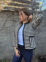 Chaqueta corta de lana merino a rayas horizontales blancas y negras, con cuello redondo y bolsillos frontales.