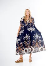 Vestido midi de algodón italiano, color azul marino con estampado en tonos blanco, beige y naranja/marrón. Presenta mangas cortas tipo murciélago, cuello en V con botones frontales y lazo desmontable para ajustar a la cintura.