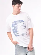 Remera blanca de algodón con estampado abstracto en tonos grises y azules.