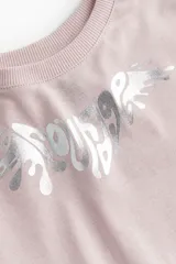 Remera corta de algodón color rosa con cuello redondo y estampado plateado en el frente.
