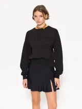 Minifalda negra confeccionada en lycra doble, con cierre lateral y tiracierre en tela base. Tiene doble capa de volados caracol en el ruedo y tajo con moño en tela complemento.