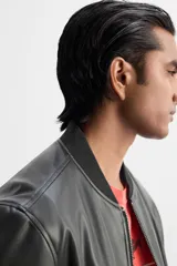 Cazadora bomber negra de efecto piel, corte relaxed fit, con cuello y puños de rib elástico, cierre frontal con cremallera, bolsillos laterales de doble vivo y bolsillo interior.