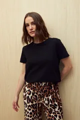 Remera negra de manga corta confeccionada en algodón liviano con textura sutil y terminaciones al ruedo con pequeños tajos laterales.