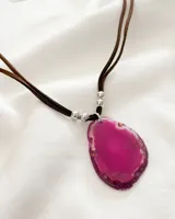 Collar con dije de piedra ágata fucsia, engarzado en metal plateado y colgante de doble cordón marrón con cuentas plateadas.