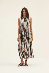 Vestido largo de corte recto con estampado tie-dye en tonos beige, marrón y negro. Tiene cuello redondo y sisas con ribete negro.