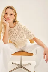 Sweater color crema tejido con punto desagujado en hilado de algodón y poliéster. Tiene ajustes en mangas y cintura, y pequeños volados en las terminaciones.