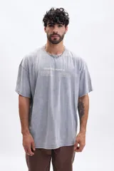 Remera de manga corta, corte oversize, color gris con efecto lavado (acid wash). Presenta un estampado minimalista en el pecho con texto que incluye "VILLA CLUB / SEASON 01".