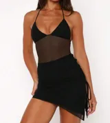 Vestido negro de corte ajustado, con escote halter y sección central de malla transparente. Incluye una minifalda negra superpuesta con frunces laterales ajustables mediante lazos.