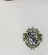Remera de algodón y poliéster color crudo, con cuello redondo y manga corta. Presenta textura acanalada horizontal, estampa localizada con escudo y ribetes en contraste en cuello y mangas.