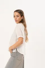 Blusa blanca de mangas cortas con cuello redondo y abotonadura frontal.