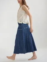 Falda midi de jean color beige, corte evasé, con bolsillos frontales y ruedo desflecado.