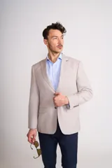 Saco sport color beige claro, de corte clásico, con solapa de muesca, dos botones frontales, bolsillos laterales con solapa y bolsillo en el pecho.