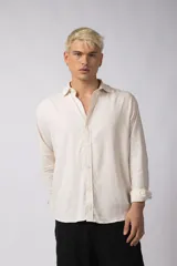 Camisa de manga larga color beige claro, con cuello abierto y calce relajado.