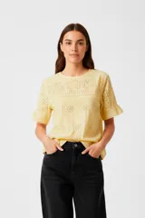 Remera amarilla de algodón con broderie y cuello redondo, mangas cortas con volados.