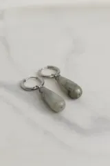 Par de aros colgantes con argolla de acero quirúrgico hipoalergénico y dije en forma de gota de piedra natural color marrón.