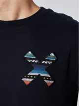 Remera azul marino de algodón orgánico con estampado en la espalda de una cruz formada por motivos geométricos de estilo étnico.