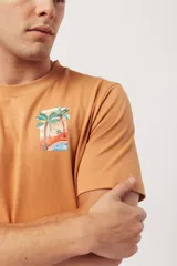 Remera de algodón color naranja claro con cuello redondo y manga corta. Presenta un pequeño estampado gráfico de temática playera en el pecho izquierdo.