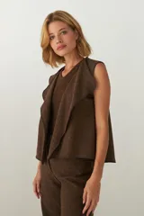 Chaleco marrón con solapas amplias y terminaciones envivadas. Diseño reversible y sin mangas.