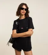 Remera negra alargada de algodón, con cuello redondo y mangas cortas. Estampa en la espalda con la palabra "TOKYO" en rojo y "JAPAN" en celeste, sobre una fotografía en blanco y negro de una calle de Tokio.
