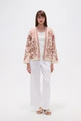 Chaqueta tipo kimono de tejido grueso color crema, con bordado floral en tonos rosados. Presenta un corte holgado y mangas anchas.