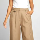 Pantalón ancho de sastre color beige de tiro alto, con cortes al frente y ajuste en la cintura.
