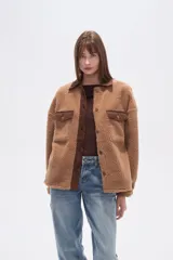 Campera estilo camisa (shacket) de tejido tipo borrego o sherpa color crema, con cuello y tapeta de pana marrón. Posee dos bolsillos frontales con tapa y botones a presión.