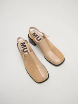 Mocasines color beige con taco bloque de madera color negro y correa trasera ajustable.