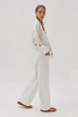 Camisa blanca de lino con bordados florales en tonos dorados y marrones en el frente y las mangas.