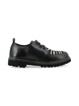 Zapato acordonado de cuero negro con suela track y detalle de pespuntes en color crudo.