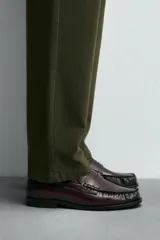 Mocasín de cuero color borgoña, con antifaz y suela negra en contraste.