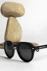 Lentes de sol negros con montura gruesa y forma geométrica.