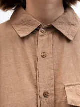 Camisa marrón claro de lino con mangas 3/4, cuello clásico, cierre frontal con botones, bolsillo de parche en el pecho y corte holgado. Marca Gaya.