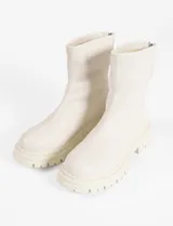 Botas cortas color crema, de cuero vegano, con suela track y cierre trasero con cremallera.