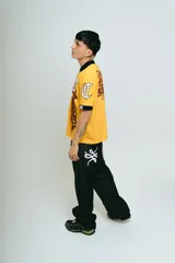 Chomba amarilla de piqué con cuello y puños negros, corte regular, bordado y aplique premium.