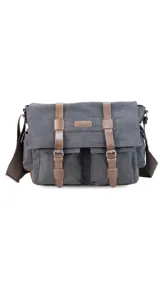 Morral de tela canvas color gris con detalles en cuero marrón. Tiene tapa con hebillas, doble bolsillo frontal, trasero y laterales. Interior espacioso con compartimento para notebook de 15". Correa de galón regulable.