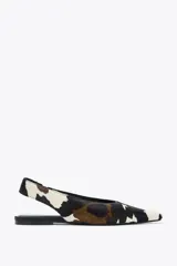 Zapato tipo bailarina destalonada en piel con pelo, con estampado animal print de vaca en blanco, marrón y negro. Tiene tira trasera con pieza elástica y acabado en punta. Suela plana de 1 cm de altura.