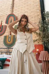 Chaleco negro de vestir, con escote en V y cierre frontal de botones dorados.