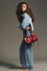 Bolso bowling color rojo con efecto craquelado. Tiene doble asa de hombro con detalles metálicos y asa bandolera extraíble. Incluye bolsillo interior con cremallera y cierre principal con cremallera.