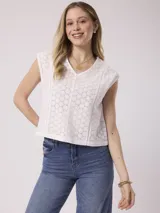 Blusa blanca de algodón con bordado calado tipo broderie, sin mangas y cuello en V.