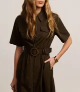 Vestido largo color verde oliva, de estructura sastrería confeccionado en tricolina. Tiene mangas cortas, cuello y cierre delantero por cremallera. Incluye cinturón de hebilla redonda con aspecto de madera.
