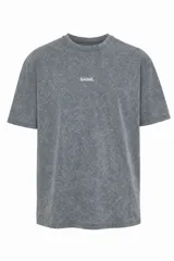 Remera de algodón con efecto stone wash gris oscuro, corte oversize y cuello redondo. Presenta un pequeño bordado blanco con la palabra "GAINS." en el centro del pecho.