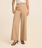 Pantalón pantalona de vestir color beige, de corte amplio y tiro alto, con trabillas en la cintura, cierre tradicional y frisos verticales.