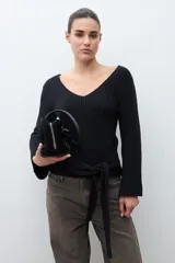 Sweater de tejido de punto negro, con escote en V pronunciado y mangas largas acampanadas. Presenta un lazo ancho anudado a la cintura.