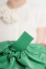 Cartera sobre azul de cuero con frunces y pespuntes diagonales.