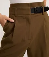 Short de sastrería color verde oliva, de corte recto y cintura alta. Presenta pliegues frontales y un detalle de medio cinturón con hebilla lateral.