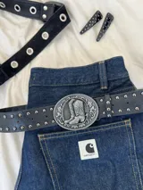 Cinturón negro de cuero sintético con hebilla plateada con diseño de botas cowboy y tachas plateadas.